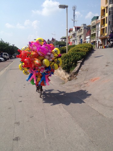 A balloon seller rides his bike in Hanoi