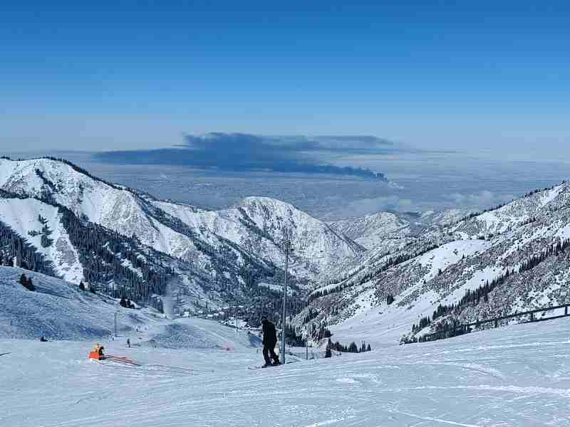 groomed piste runs at shymbulak mountain resort with a view of almaty in the distance