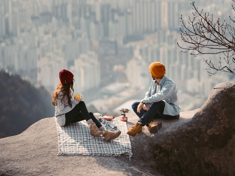 couple sitting on a blanket having a picnic high above a city
